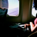 woman riding in airplane while watching at window