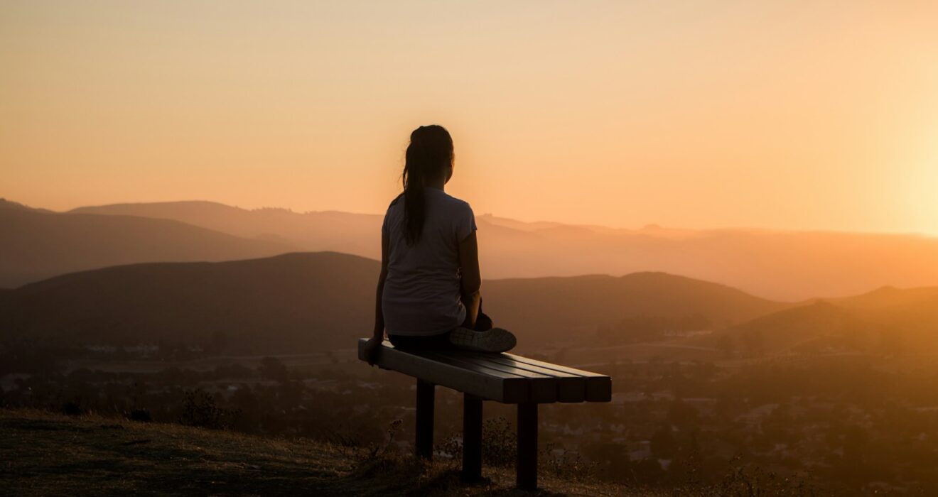 woman sitting on bench over viewing mountain