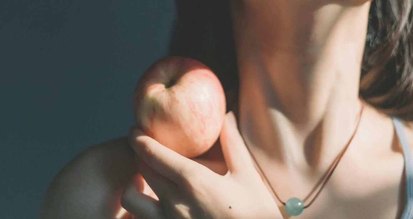 woman in silver necklace holding apple