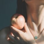 woman in silver necklace holding apple