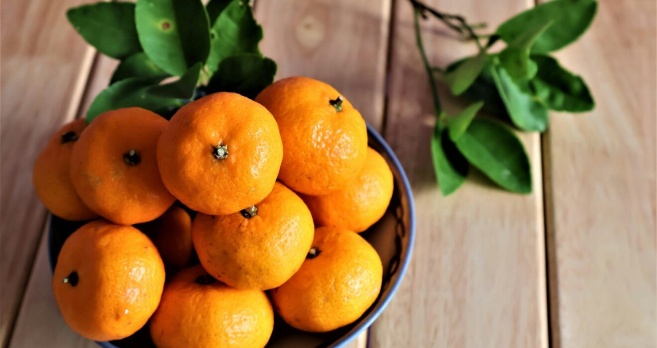 a bowl of oranges on a wooden table