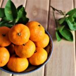 a bowl of oranges on a wooden table