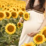 Pregnant woman poses in a sunflower field.