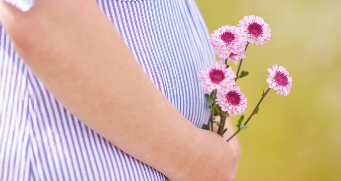 pregnant woman holding petaled flowers