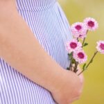 pregnant woman holding petaled flowers